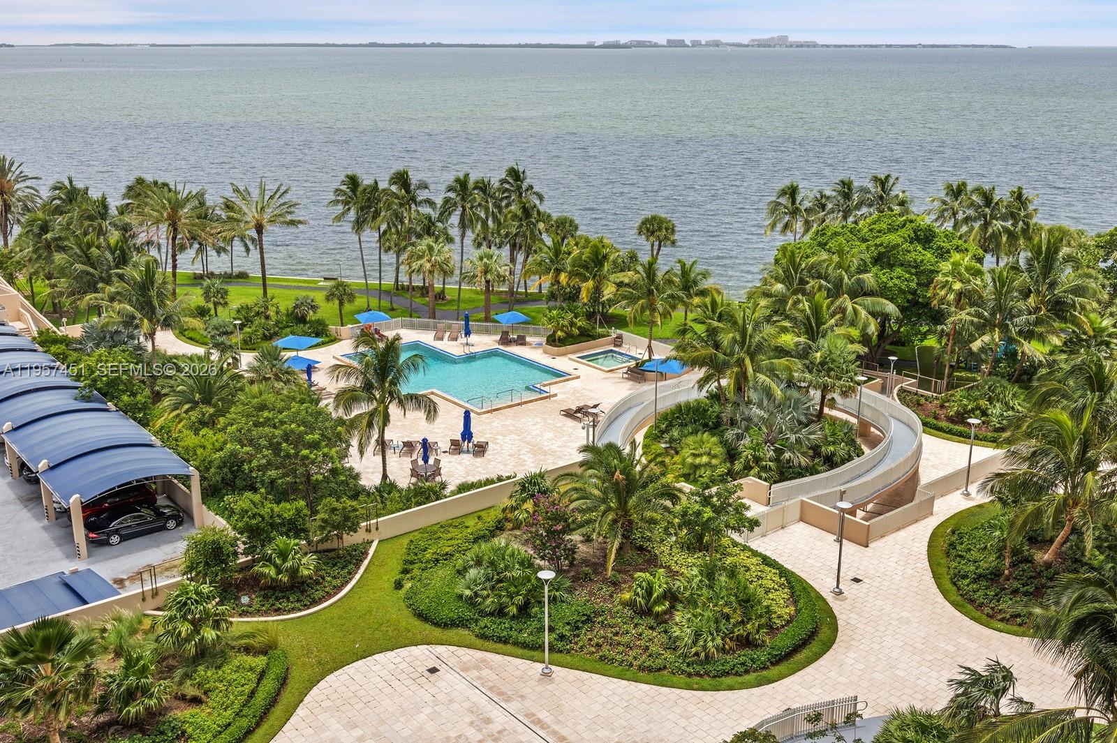 An aerial view shows a swimming pool, hot tub, and parking area near the ocean — 2 Grove Isle Dr # B907, Miami FL 33133, MIAMI, FL