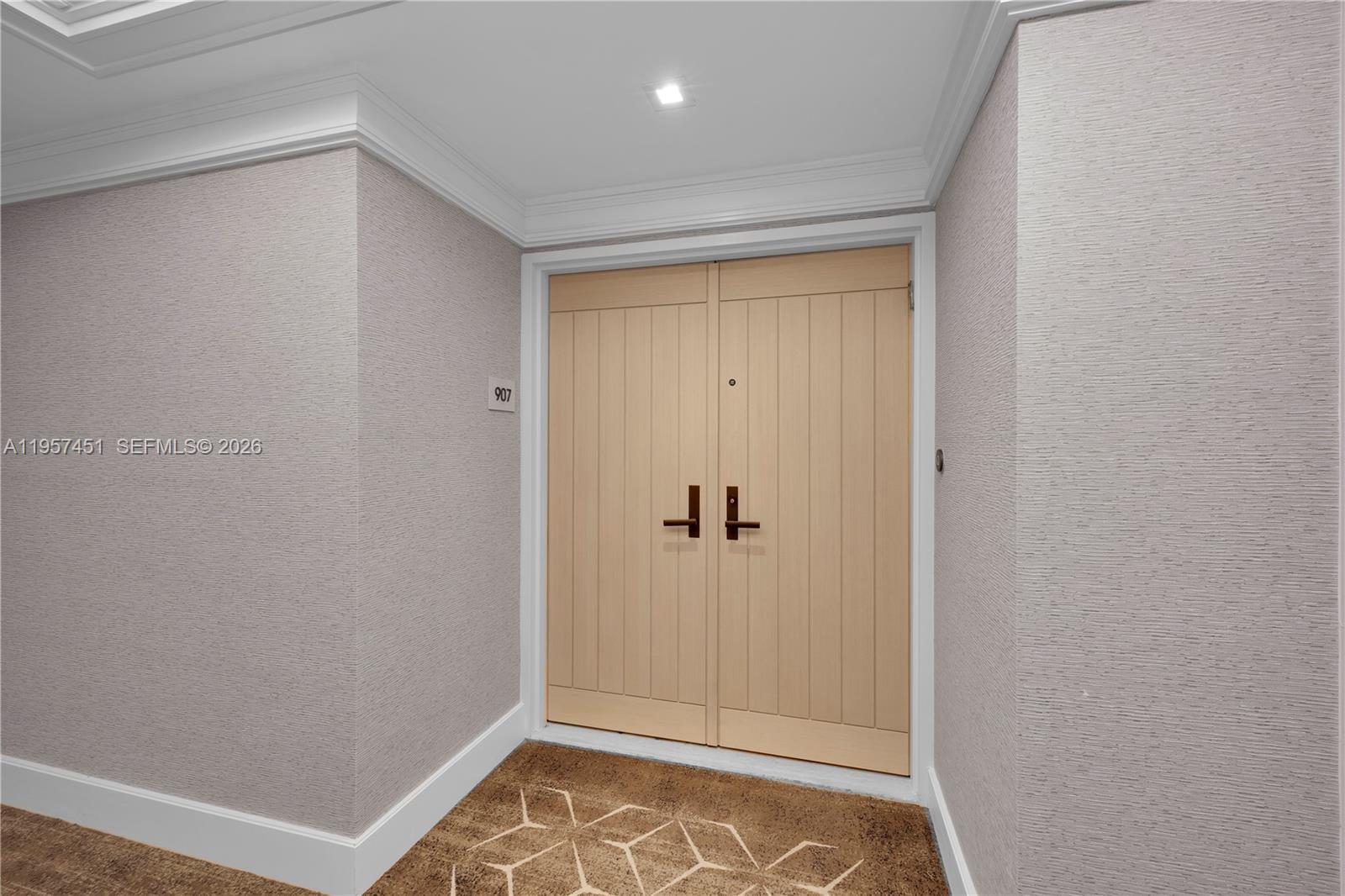 A double door with light wood paneling is set into a textured gray wall — 2 Grove Isle Dr # B907, Miami FL 33133, MIAMI, FL