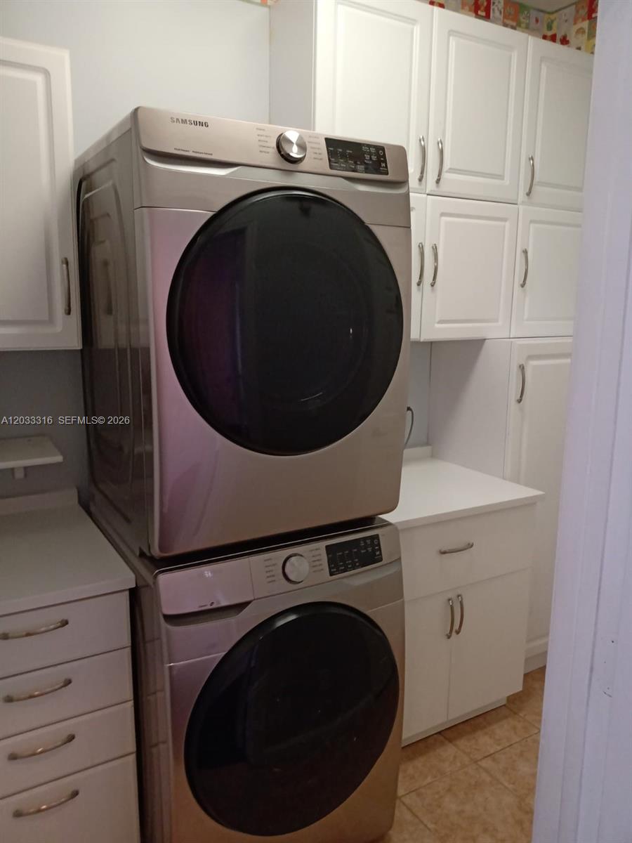 A laundry room features a stacked Samsung washer and dryer set with white cabinetry — 8682 Via Ancho Rd, Boca Raton FL 33433, BOCA RATON, FL