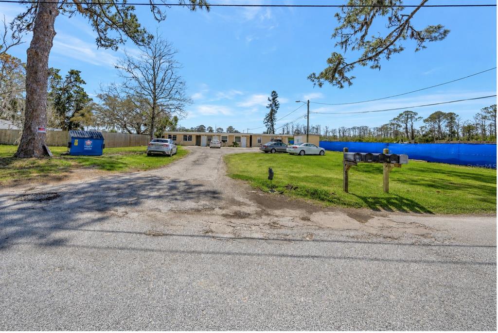 A single-story apartment building sits at the end of a gravel driveway with parked cars — 5100 SOUTH ROAD, NEW PORT RICHEY, FL
