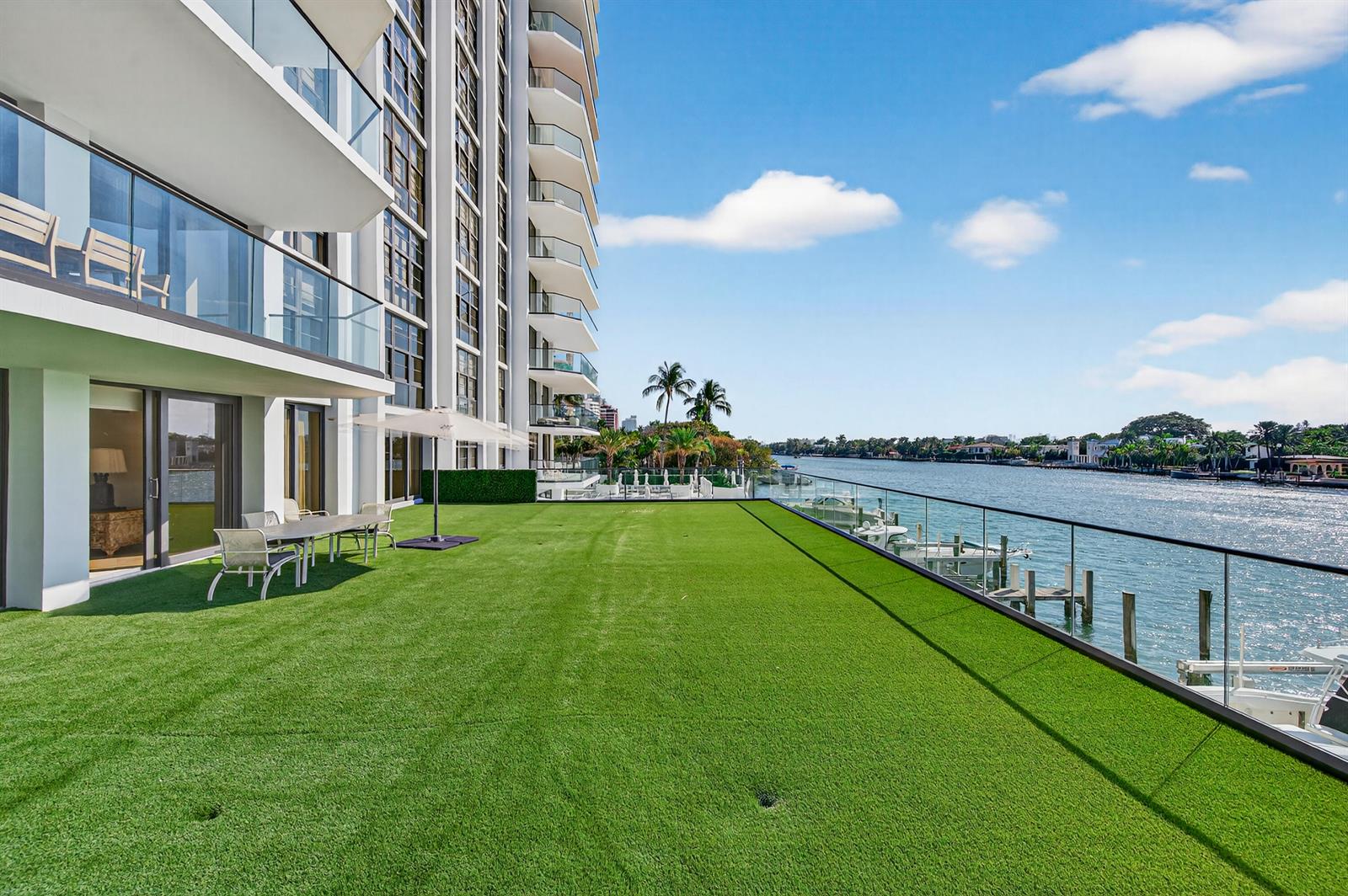 A large, artificial grass terrace overlooks a waterway with a modern high-rise building nearby — 5500 Collins Avenue # 302, Miami Beach FL 33140, MIAMI BEACH, FL