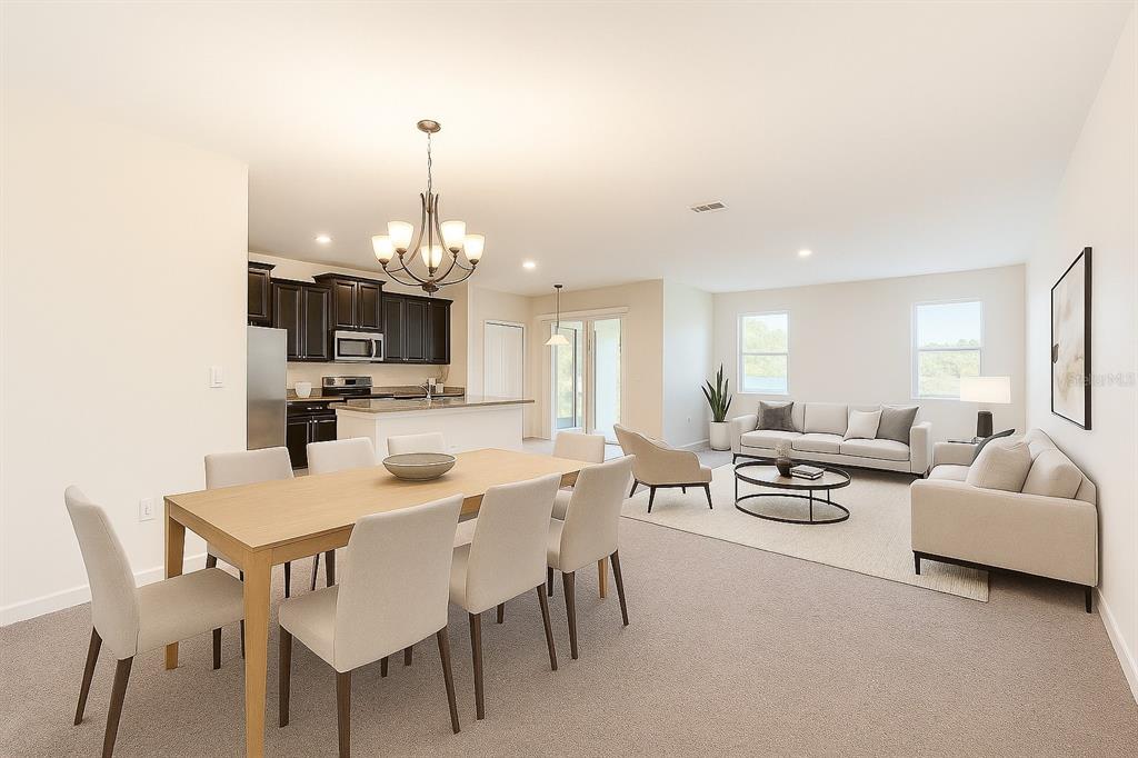An open-concept living and dining area with a kitchen, light carpeting, and neutral furniture — 2037 LAKE SIDE AVENUE, DAVENPORT, FL