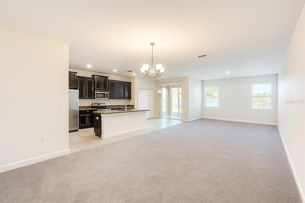An open-concept living area features a kitchen with dark cabinets and gray carpeted flooring — 2037 LAKE SIDE AVENUE, DAVENPORT, FL