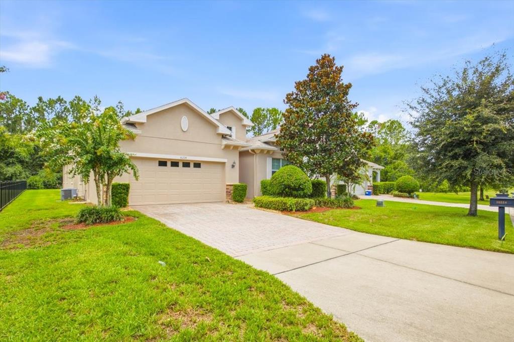 A single-story house with a beige stucco exterior, a two-car garage, and a paved driveway — 16224 SW MEAD STREET, CLERMONT, FL