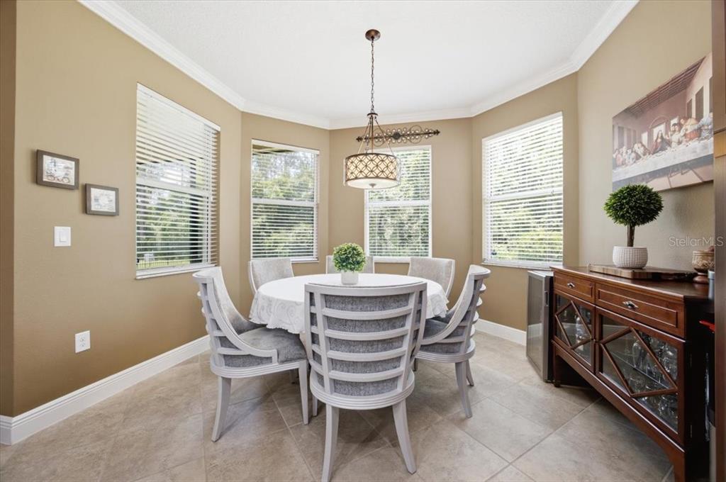 A dining room with a round table, four chairs, a chandelier, and a wooden sideboard — 16224 SW MEAD STREET, CLERMONT, FL