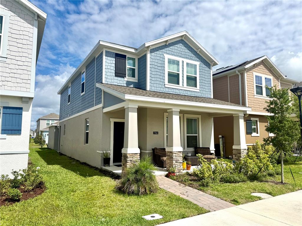 A two-story house with blue shingle siding, a stone-based front porch, and a paved walkway — 1964 TOHOQUA BOULEVARD, KISSIMMEE, FL