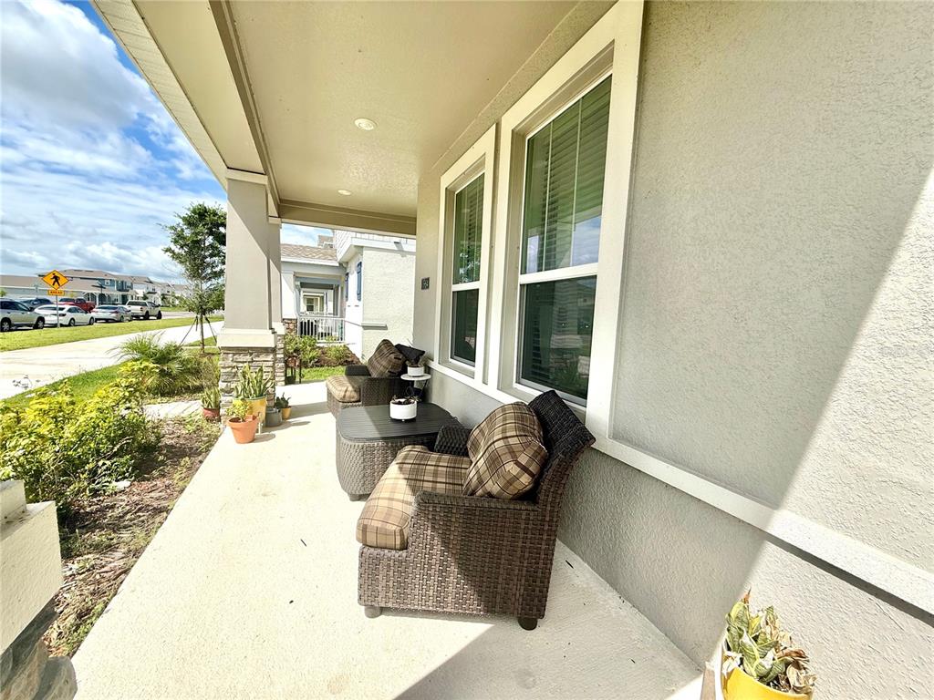 A covered front porch features two wicker chairs, a small table, and potted plants — 1964 TOHOQUA BOULEVARD, KISSIMMEE, FL