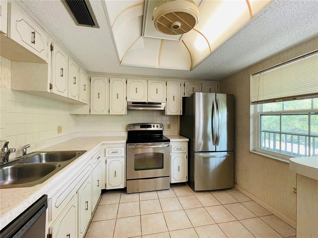 A kitchen with white cabinets, stainless steel appliances, tile flooring, and a recessed ceiling light — 840 VIRGINIA STREET UNIT 303, DUNEDIN, FL