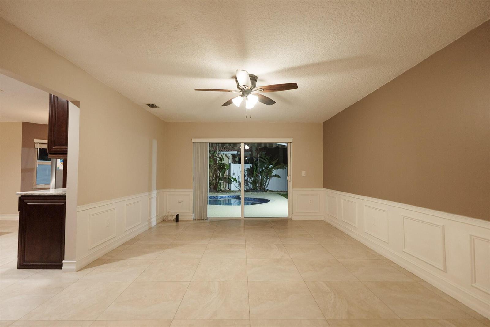 A dining room with tile floors, wainscoting, and a sliding glass door overlooking a pool — 7251 NW 24th Court, Margate FL 33063, MARGATE, FL