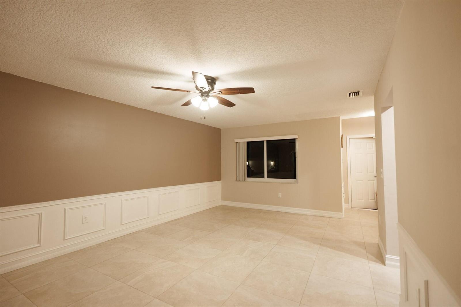An empty room with beige walls, white wainscoting, tile flooring, and a ceiling fan — 7251 NW 24th Court, Margate FL 33063, MARGATE, FL