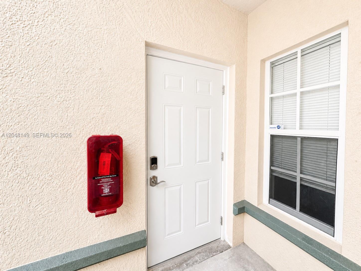 A white door with a keypad lock sits next to a wall-mounted red fire extinguisher — 2452 Centergate Dr # 102, Miramar FL 33025, MIRAMAR, FL
