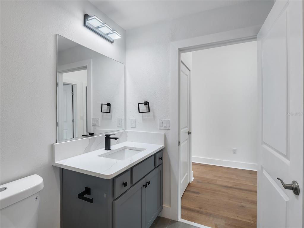 A bathroom features a gray vanity with a white countertop, a mirror, and black fixtures — 4144 SILVANA WAY, THE VILLAGES, FL