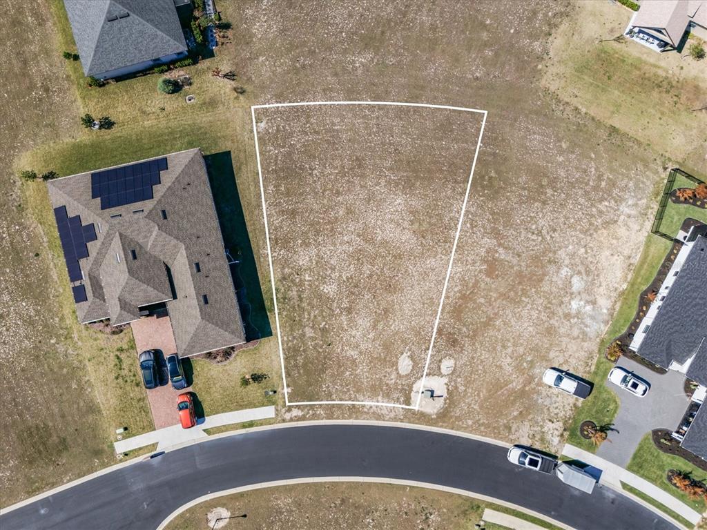 An aerial view shows a vacant residential lot outlined in white between two existing houses — 473 WATERFERN TRAIL DRIVE, AUBURNDALE, FL
