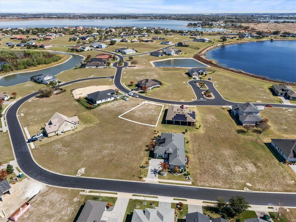 An aerial view shows a vacant residential lot outlined in white within a suburban neighborhood — 473 WATERFERN TRAIL DRIVE, AUBURNDALE, FL