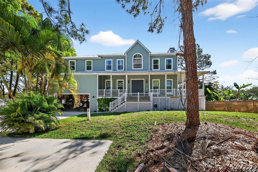 A two-story light blue house with a wrap-around porch and an attached garage — 4433 SWEETWATER DRIVE, TAMPA, FL
