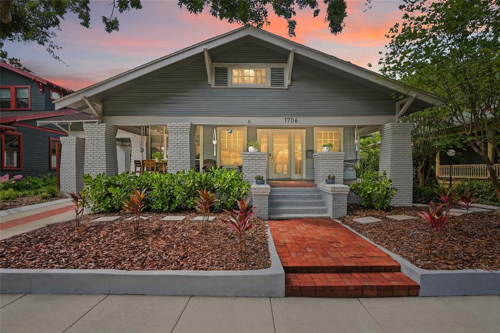 A gray bungalow with a brick walkway, front porch, and landscaped yard at sunset — 1706 W JETTON AVENUE, TAMPA, FL