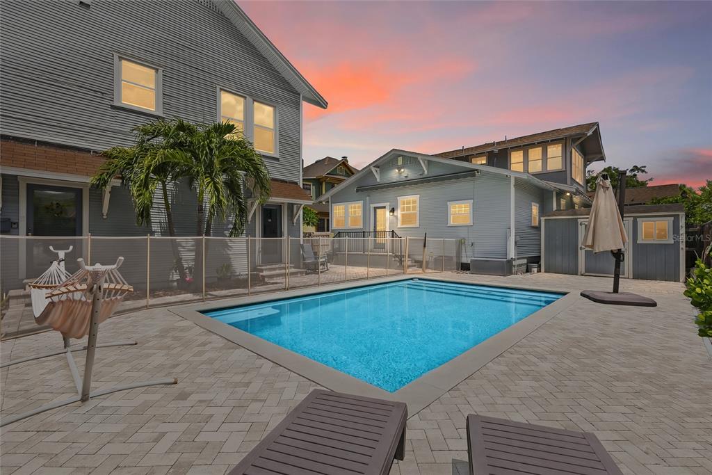 A backyard features a rectangular swimming pool, a paved patio, and two gray houses — 1706 W JETTON AVENUE, TAMPA, FL