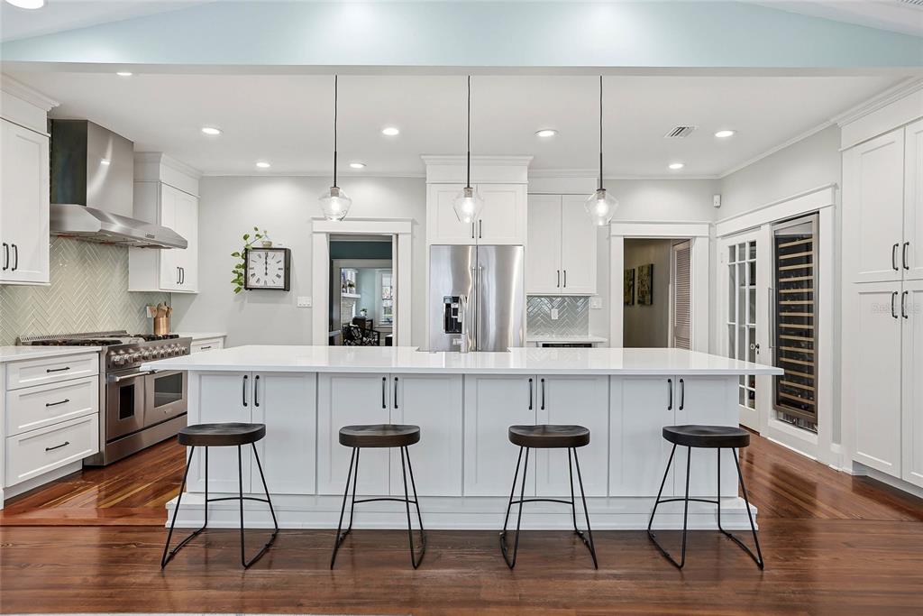A white kitchen features a large center island with four stools and stainless steel appliances — 1706 W JETTON AVENUE, TAMPA, FL