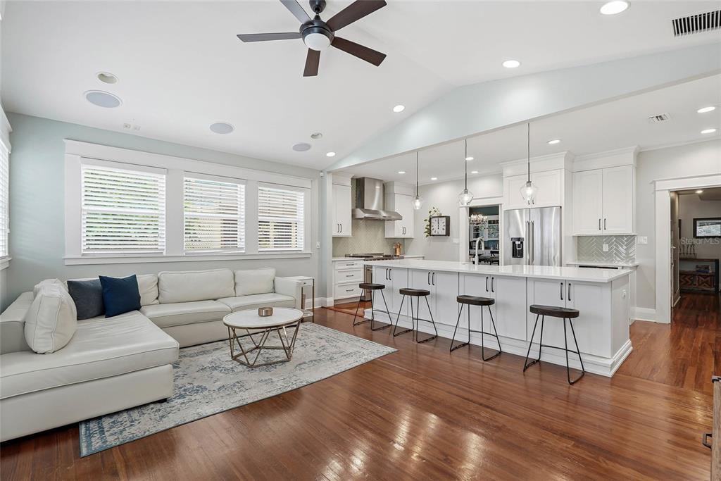 A bright open-concept living room and kitchen featuring white cabinetry, an island, and hardwood floors — 1706 W JETTON AVENUE, TAMPA, FL