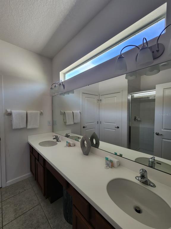 A bathroom features a double vanity with white countertops, dark wood cabinets, and a large mirror — 4468 MONADO DRIVE, KISSIMMEE, FL