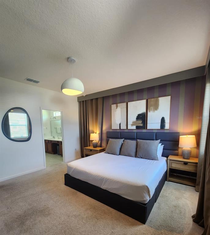 A bedroom features a king bed, striped accent wall, and an attached bathroom — 4468 MONADO DRIVE, KISSIMMEE, FL