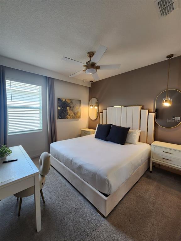 A bedroom features a king bed with a tall headboard, desk, and two hanging mirrors — 4468 MONADO DRIVE, KISSIMMEE, FL