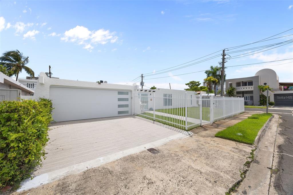 A white house with a garage and fenced yard sits along a street — 2 CALLE MAR DE IRLANDA, CAROLINA, PR