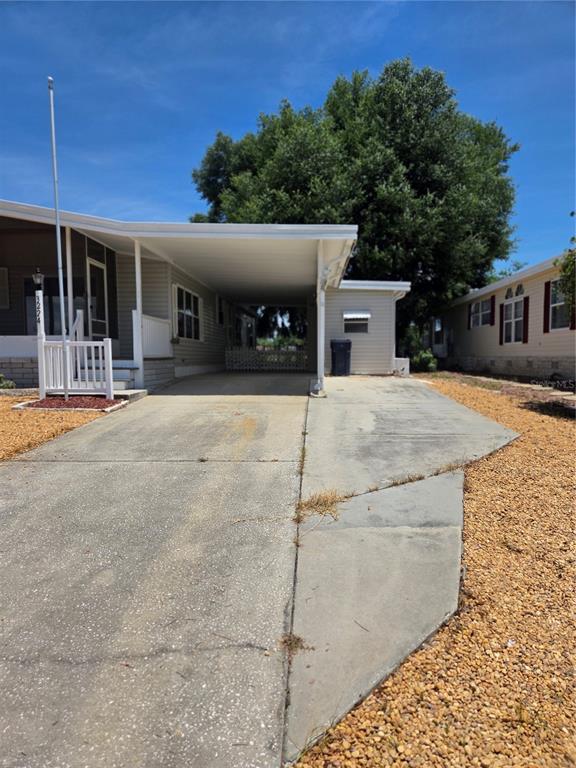 A manufactured home features a concrete driveway, a covered carport, and a white railing — 3224 MANATEE ROAD, TAVARES, FL