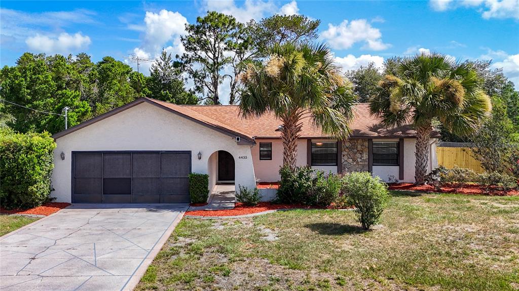A single-story house with a garage, palm trees, and a stone facade under a blue sky — 4435 BAYRIDGE COURT, SPRING HILL, FL