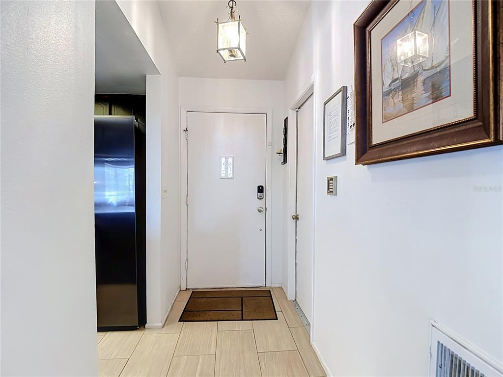 A white entryway features a front door, tile flooring, a hanging light, and wall art — 4435 BAYRIDGE COURT, SPRING HILL, FL