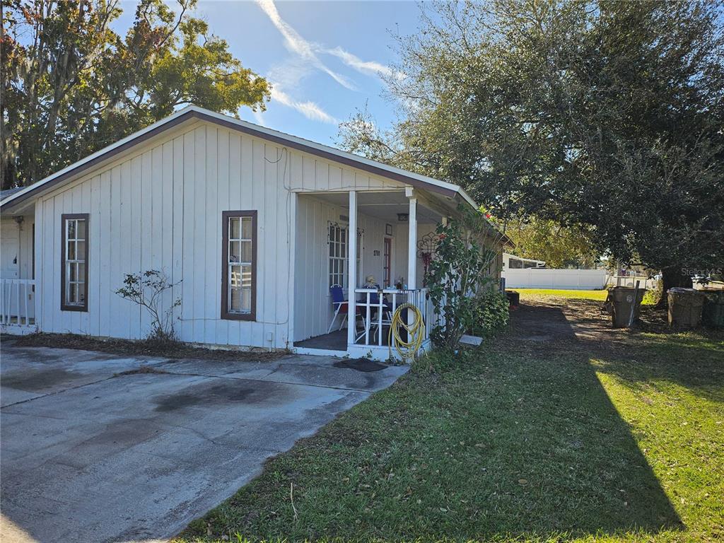 A single-story house with white vertical siding, a front porch, and a concrete driveway — 2761 MICHIGAN AVENUE, KISSIMMEE, FL
