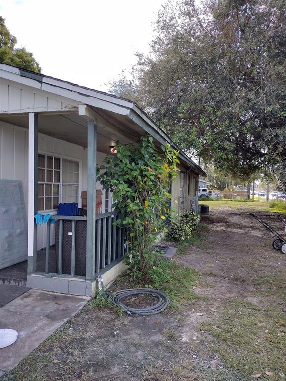 A side view of a house with a covered porch, a railing, and a yard — 2761 MICHIGAN AVENUE, KISSIMMEE, FL