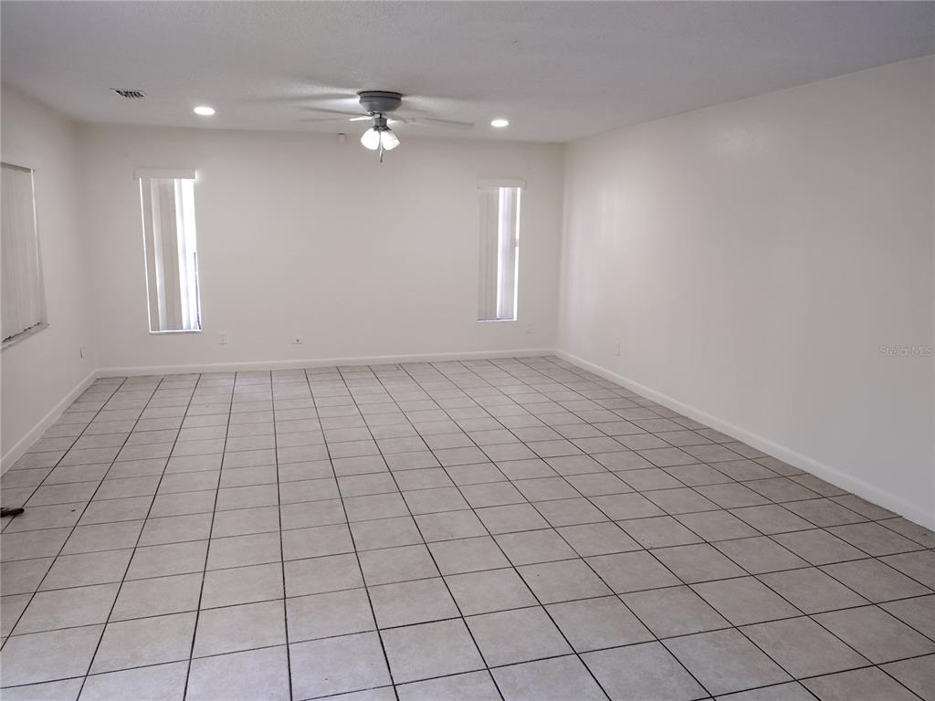 An empty room features white walls, light-colored tile flooring, and a ceiling fan — 2761 MICHIGAN AVENUE, KISSIMMEE, FL