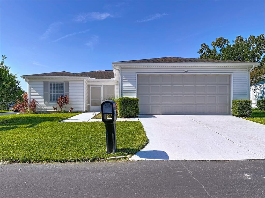 A single-story white house with a two-car garage and a front lawn — 11205 COREY PAVIN LANE, SAN ANTONIO, FL