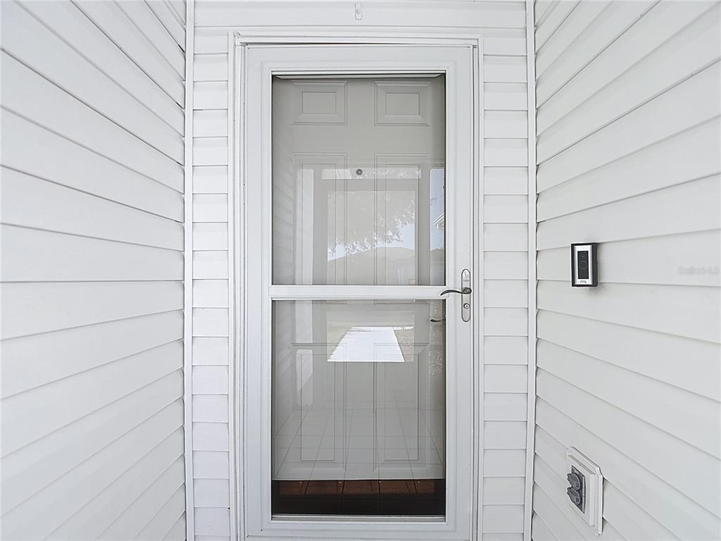 A white storm door is installed in a white vinyl-sided entryway — 11205 COREY PAVIN LANE, SAN ANTONIO, FL