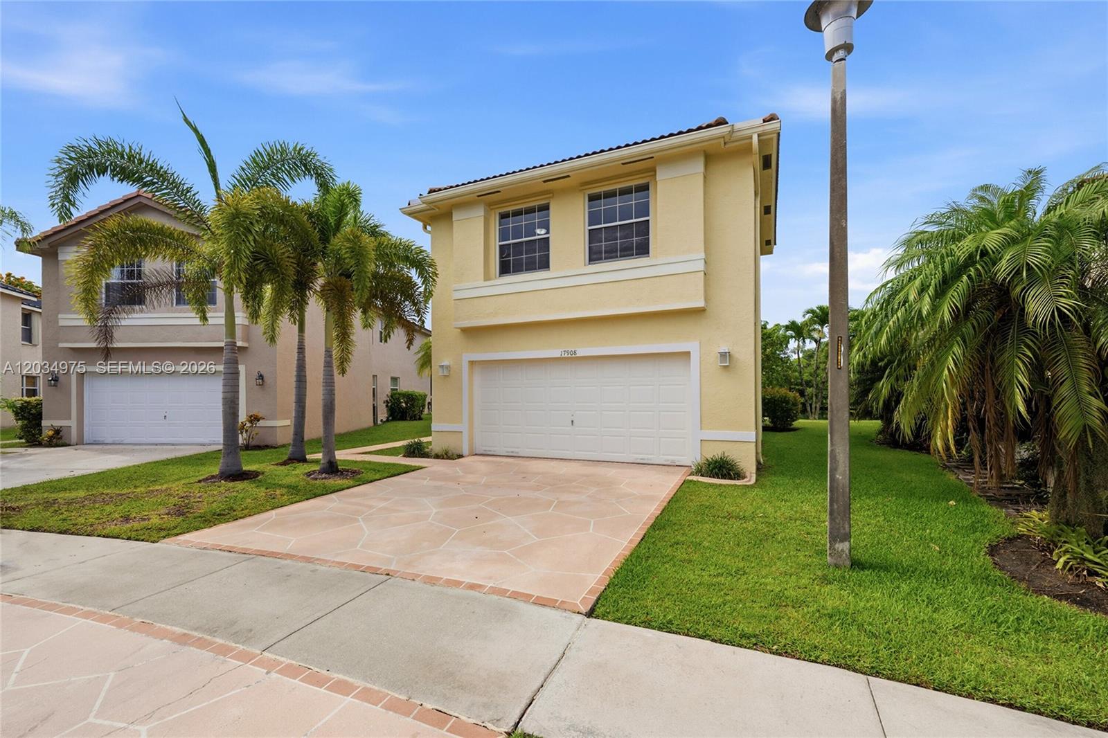 A two-story yellow house with a white garage door and palm trees in the yard — 17908 SW 30th Ct, Miramar FL 33029, MIRAMAR, FL