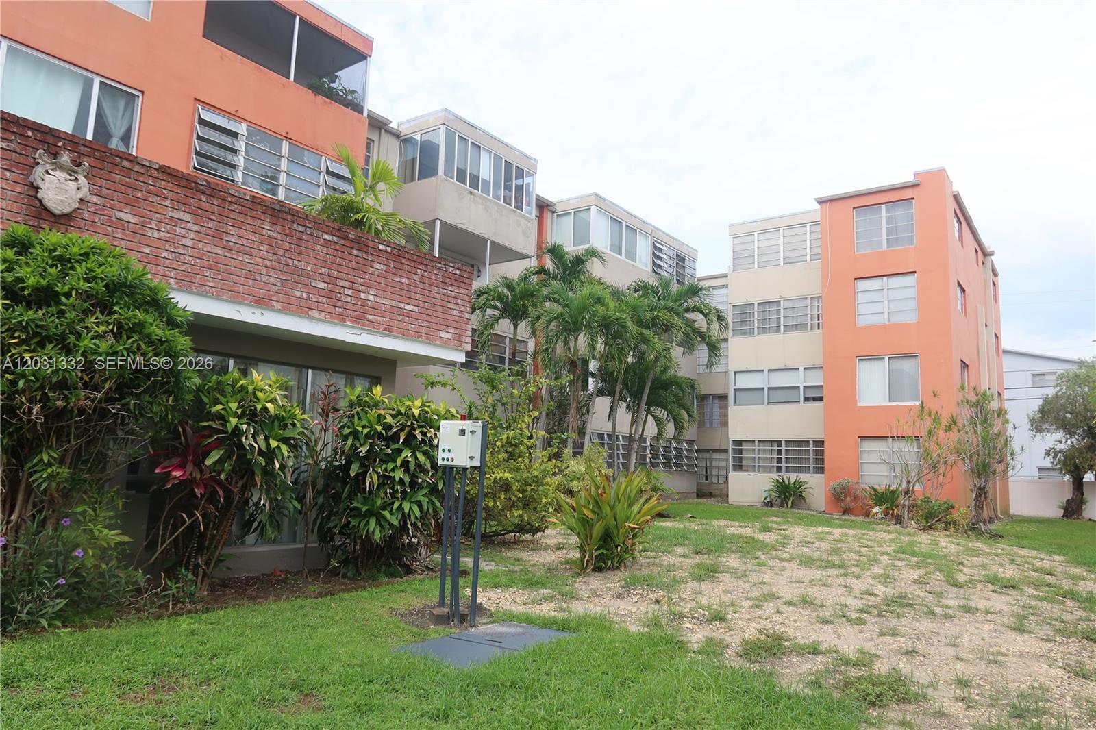 The exterior of a multi-story apartment complex features orange and beige stucco walls — 1850 NE 169th St # 312, North Miami Beach FL 33162, NORTH MIAMI BEACH, FL