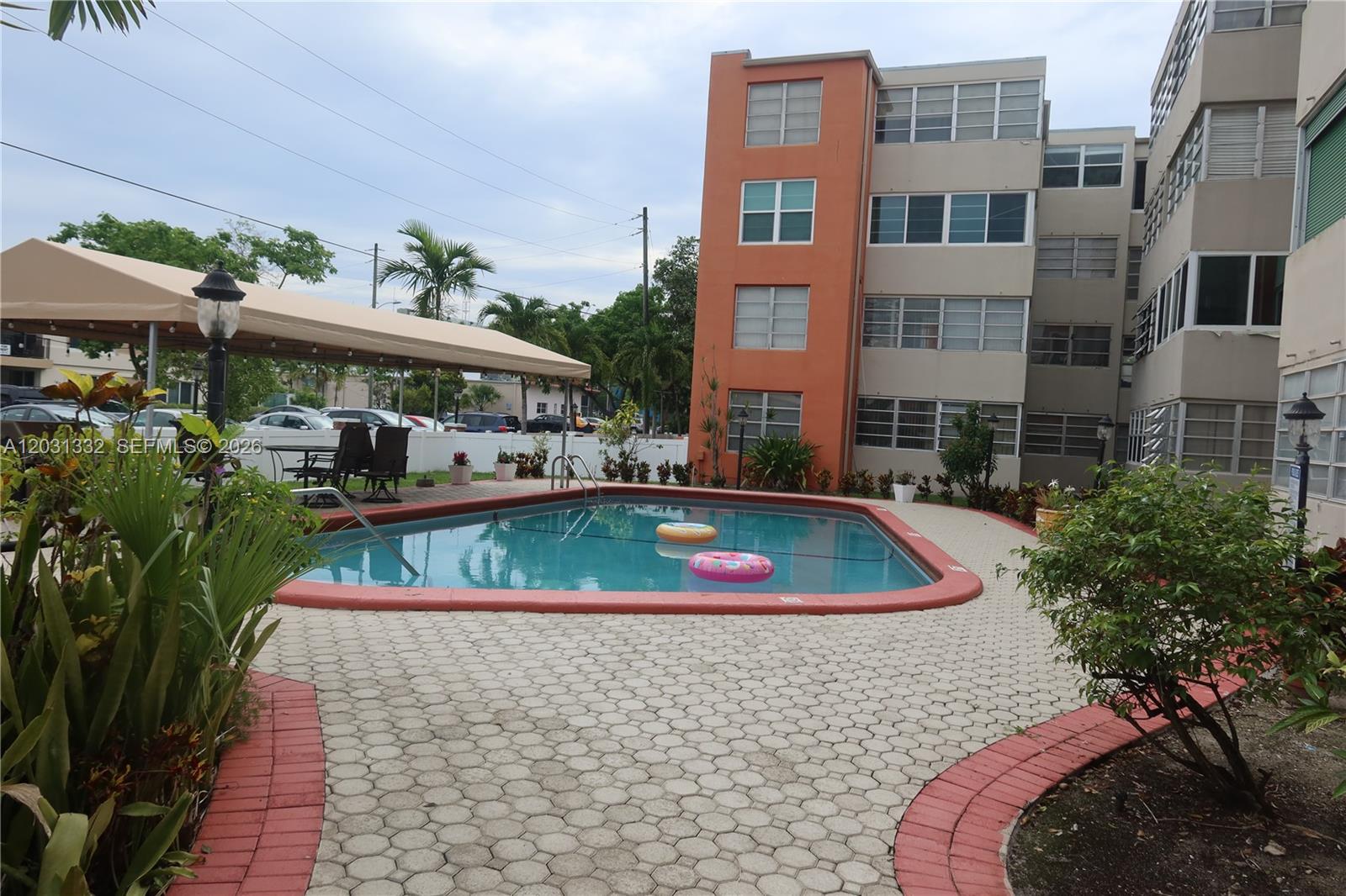 A swimming pool with two floats sits on a patio beside a multi-story apartment building — 1850 NE 169th St # 312, North Miami Beach FL 33162, NORTH MIAMI BEACH, FL