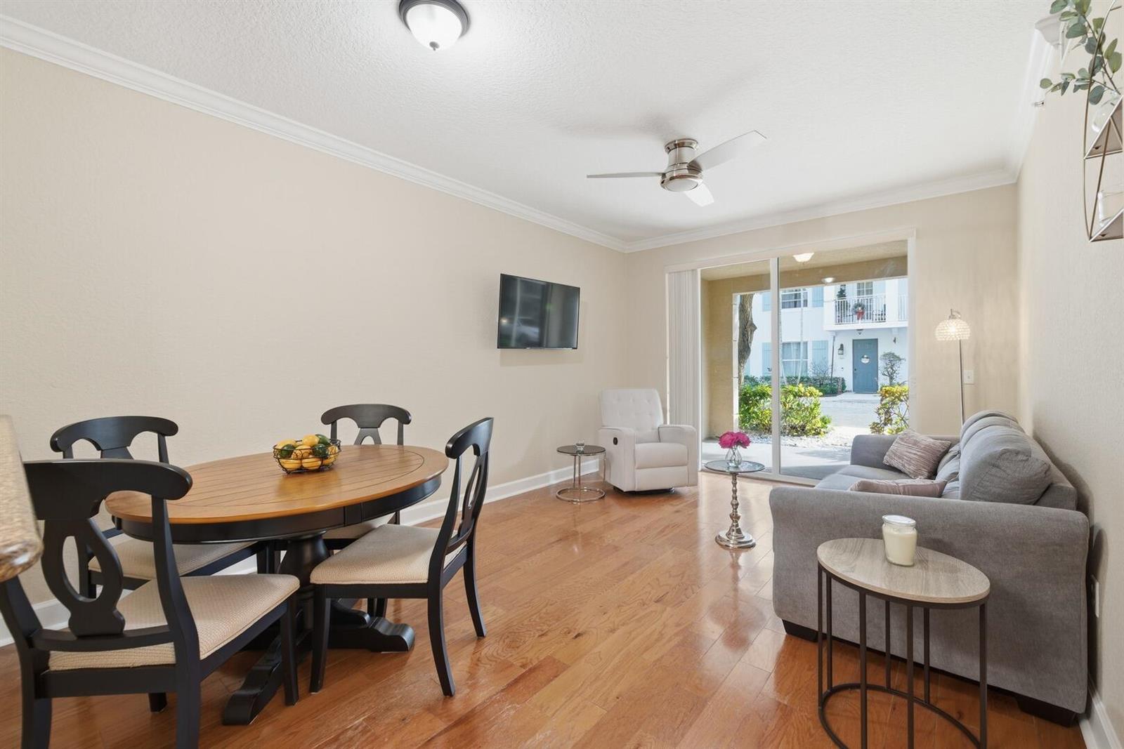 A living and dining area features hardwood floors, a ceiling fan, and a sliding glass door — 4 Renaissance Way # 110, Boynton Beach FL 33426, BOYNTON BEACH, FL