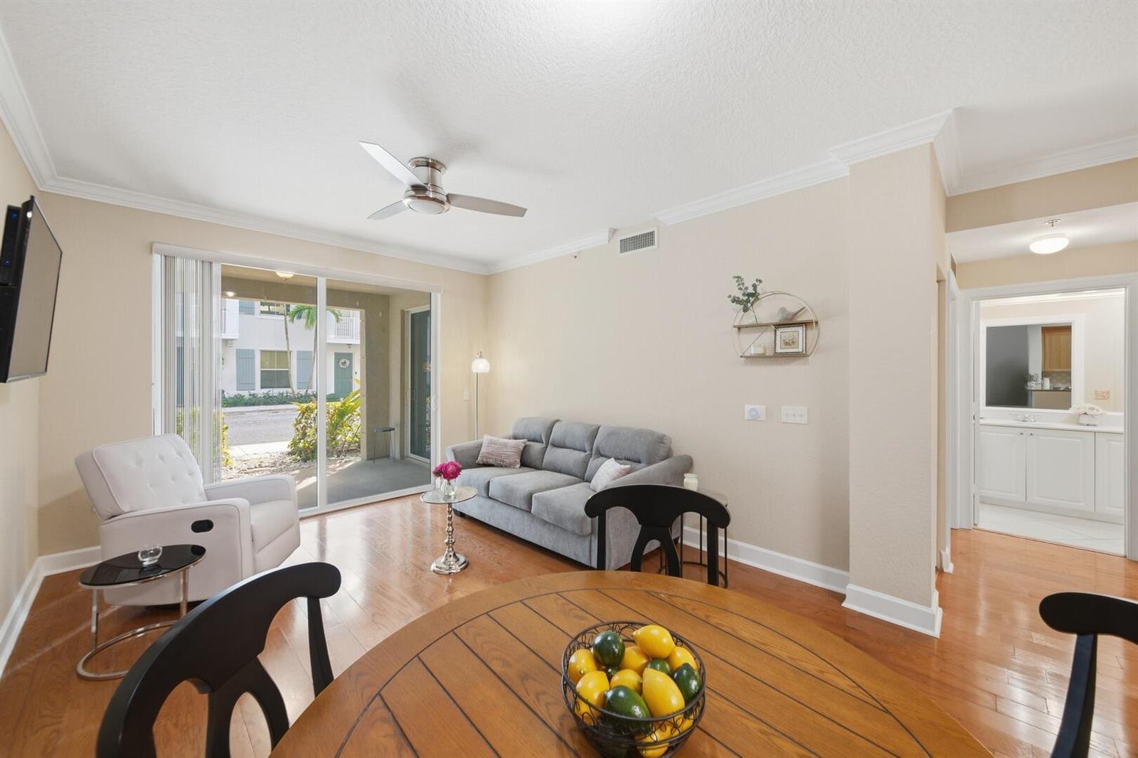 A living room with hardwood floors, a grey sofa, and a sliding glass door — 4 Renaissance Way # 110, Boynton Beach FL 33426, BOYNTON BEACH, FL