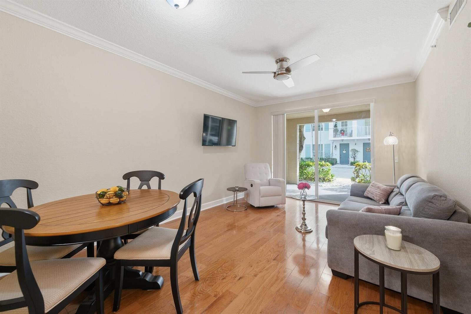 A living and dining area with hardwood floors, a gray sofa, and a sliding glass door — 4 Renaissance Way # 110, Boynton Beach FL 33426, BOYNTON BEACH, FL