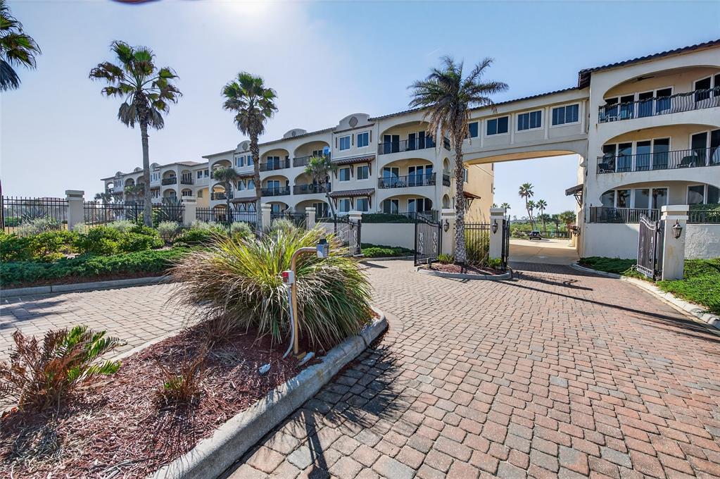 A paved driveway leads to the entrance of a multi-story apartment building with palm trees — 2450 N OCEAN SHORE BOULEVARD UNIT 115, FLAGLER BEACH, FL
