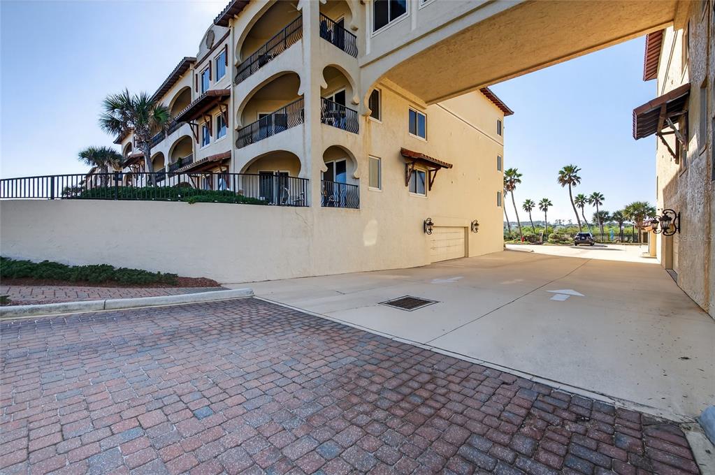 An exterior view of a multi-story building with a covered driveway and arched balconies — 2450 N OCEAN SHORE BOULEVARD UNIT 115, FLAGLER BEACH, FL