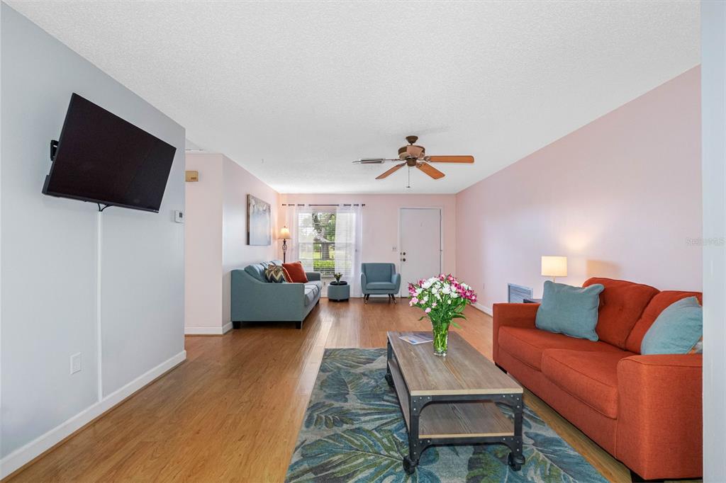 A living room features light walls, wood flooring, two sofas, and a ceiling fan — 12200 VONN ROAD UNIT 6B, LARGO, FL