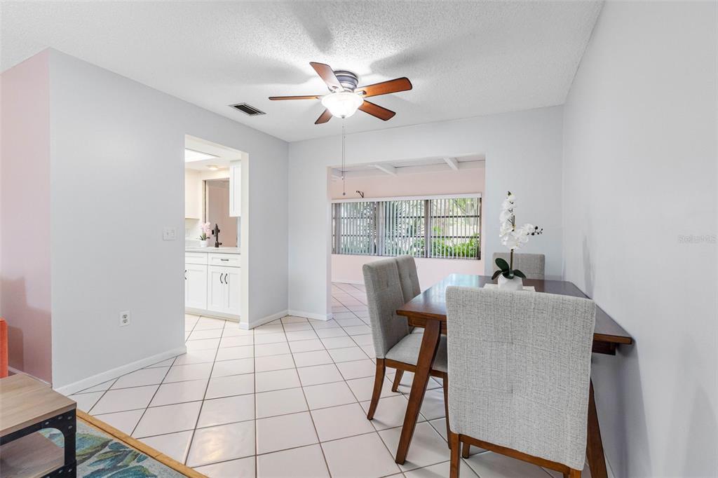 A dining area with a wooden table, grey upholstered chairs, and tiled flooring — 12200 VONN ROAD UNIT 6B, LARGO, FL