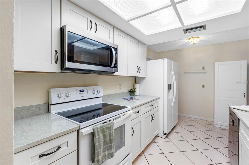 A kitchen with white cabinets, stainless steel appliances, and light-colored countertops on a tiled floor — 12200 VONN ROAD UNIT 6B, LARGO, FL