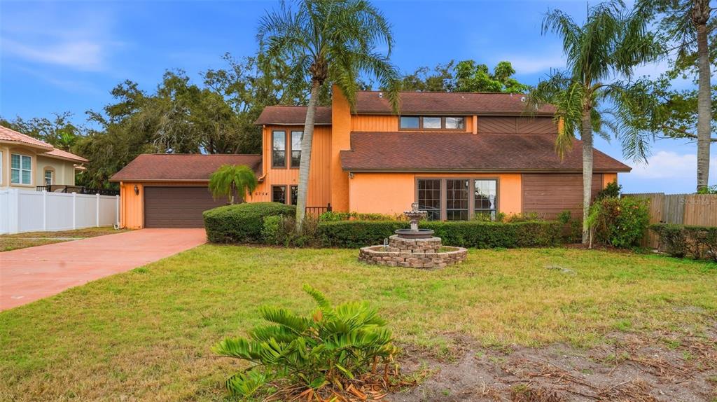 A two-story orange house with a brown roof, a stone fountain, and palm trees — 6754 31ST STREET S, ST PETERSBURG, FL