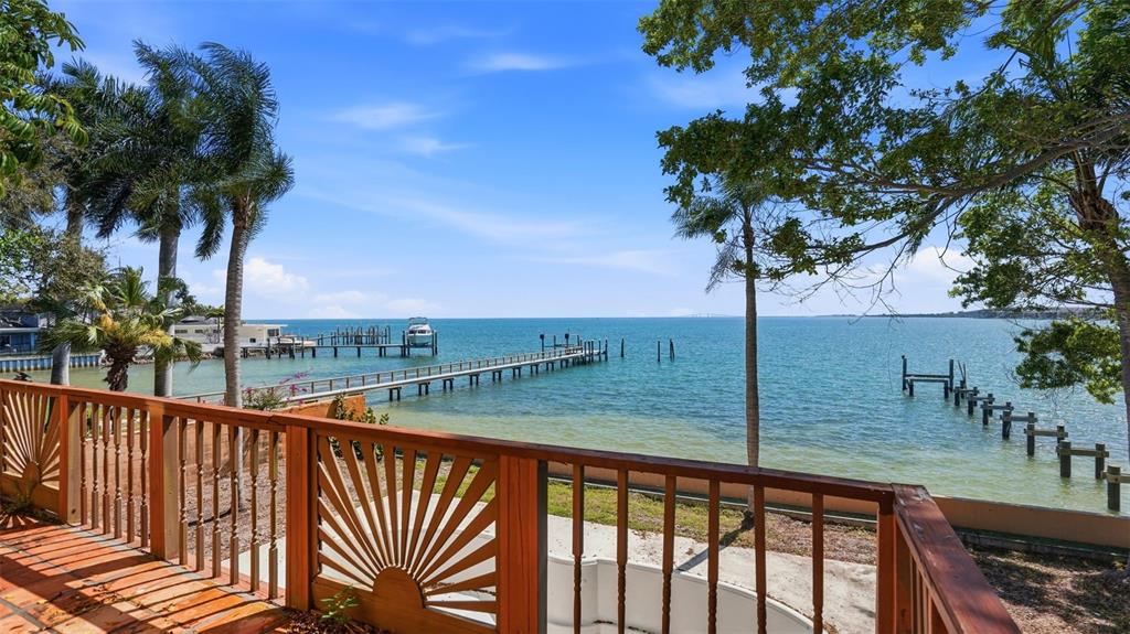 A wooden deck with decorative railings overlooks a bay with two long boat docks — 6754 31ST STREET S, ST PETERSBURG, FL