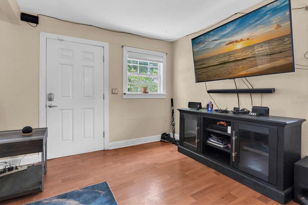 A living room with wood-look flooring, a wall-mounted television, and a black media console — 3443 21ST STREET N, ST PETERSBURG, FL