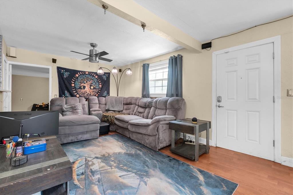 A living room features a large gray sectional sofa, a patterned rug, and a white door — 3443 21ST STREET N, ST PETERSBURG, FL